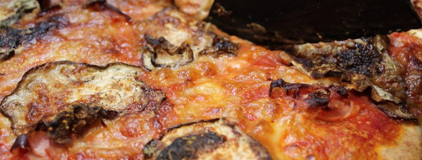 Ricetta semplice per pizza in teglia. Pizza con melanzane, prosciutto cotto e parmigiano in cottura